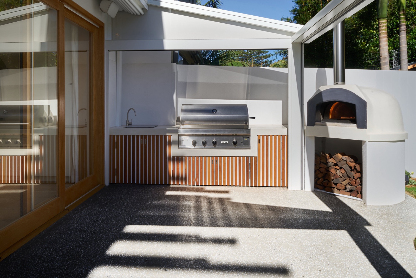 Outdoor kitchen with wood-fired oven by Perelli Group